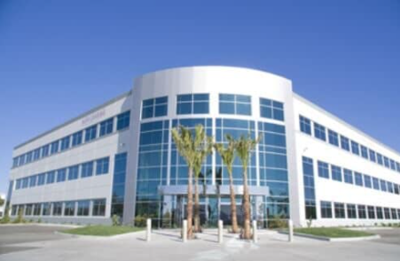 A large white building with a lot of windows and palm trees in front of it