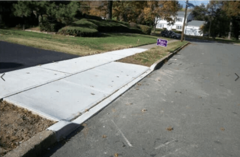 A sidewalk with a purple sign on the side of it