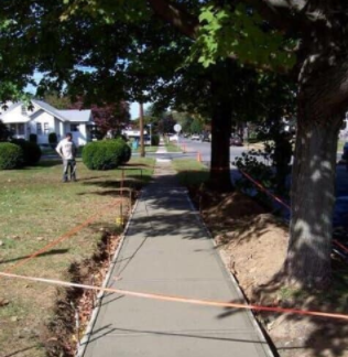 A concrete sidewalk is being built in a residential area