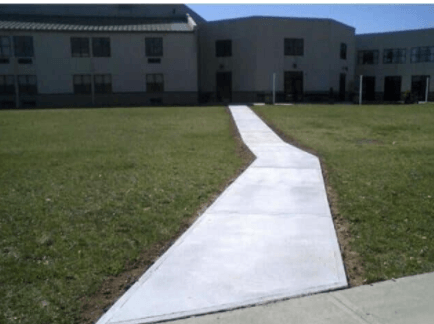 A concrete walkway in front of a large building