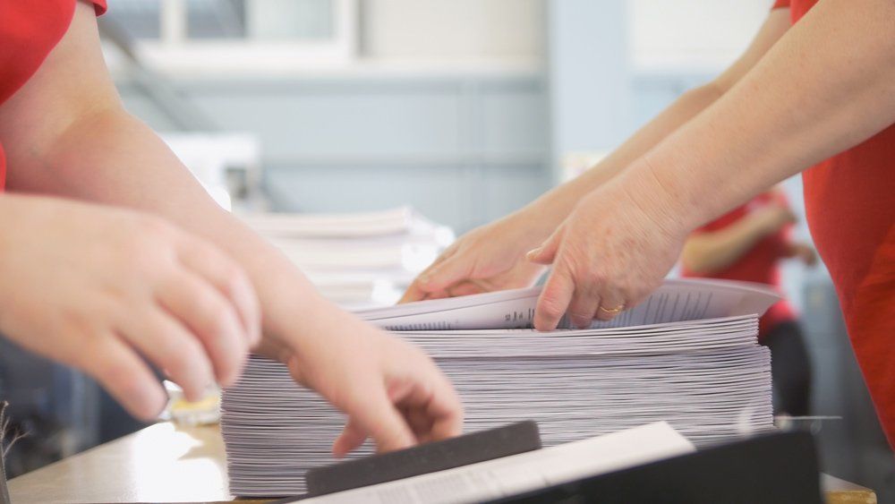 Hands of Female Workers Shift the Paper Stacks — Greensboro, NC — Copy King Printing
