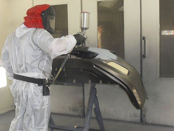 Car Remodeling — Man Painting Car Bumper in Traverse City, MI