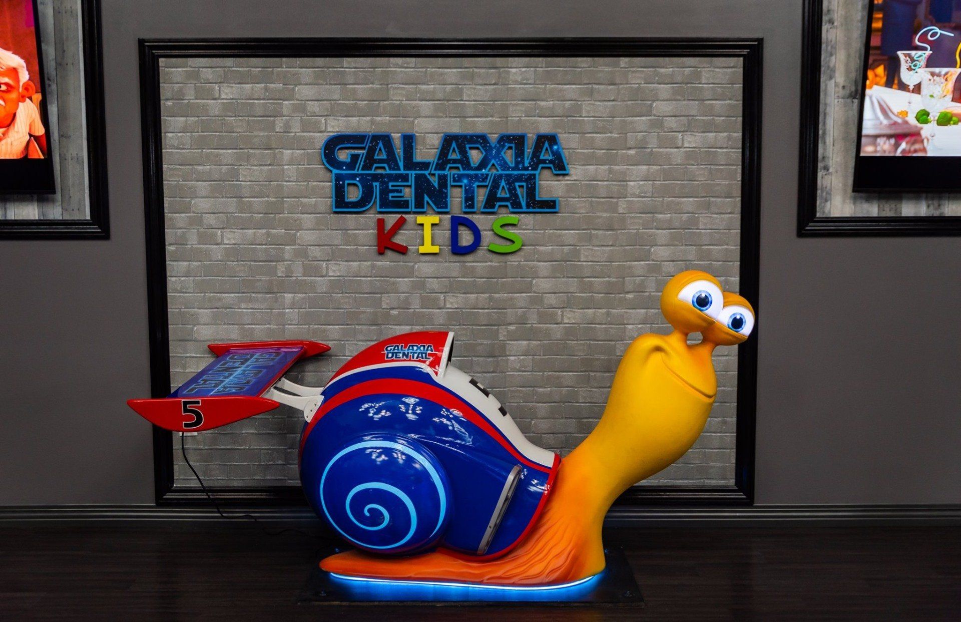 A statue of a snail in front of a sign that says galeria dental kids