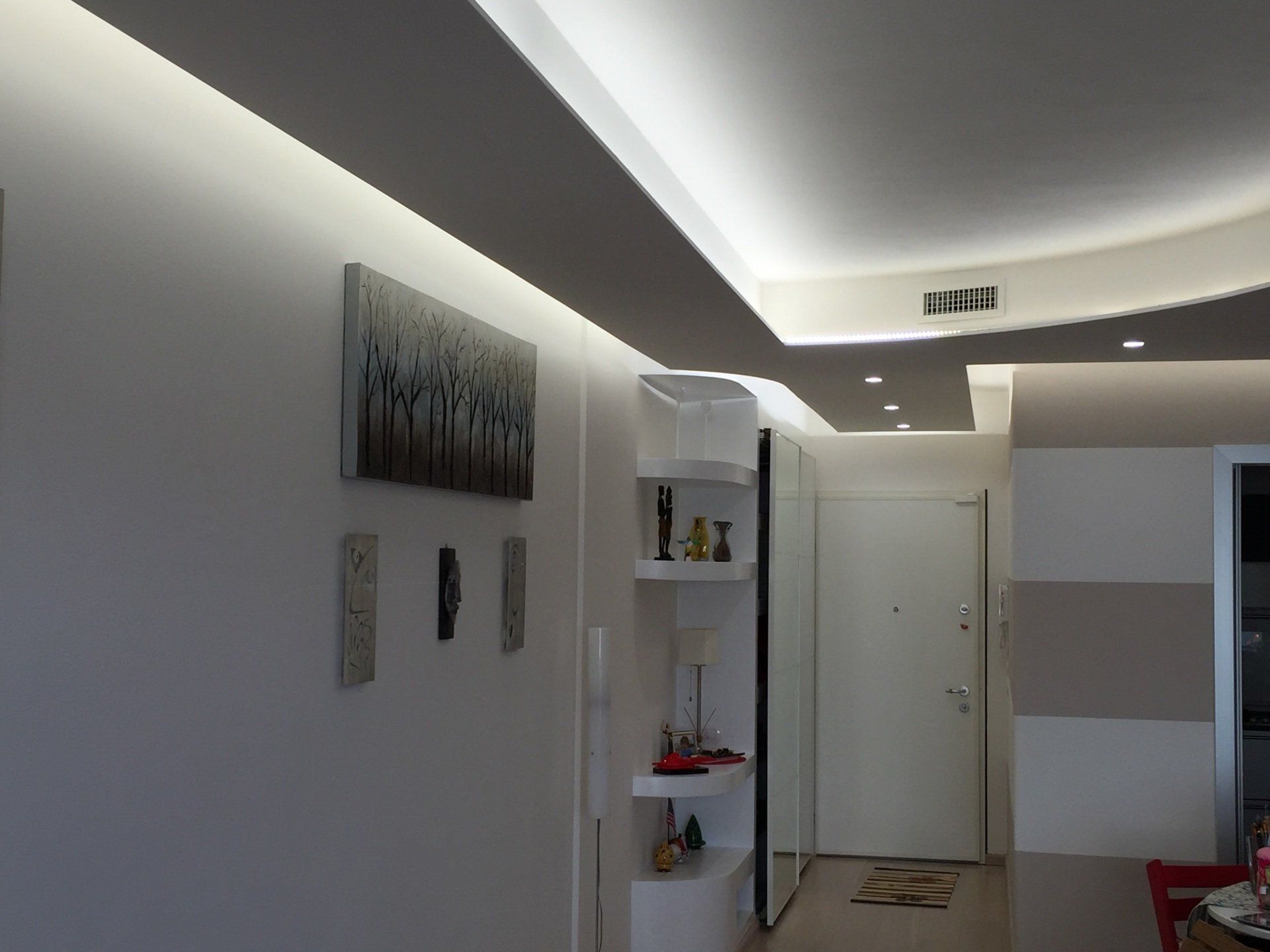 Un corridoio moderno e ben illuminato, con pareti bianche e faretti a incasso.
