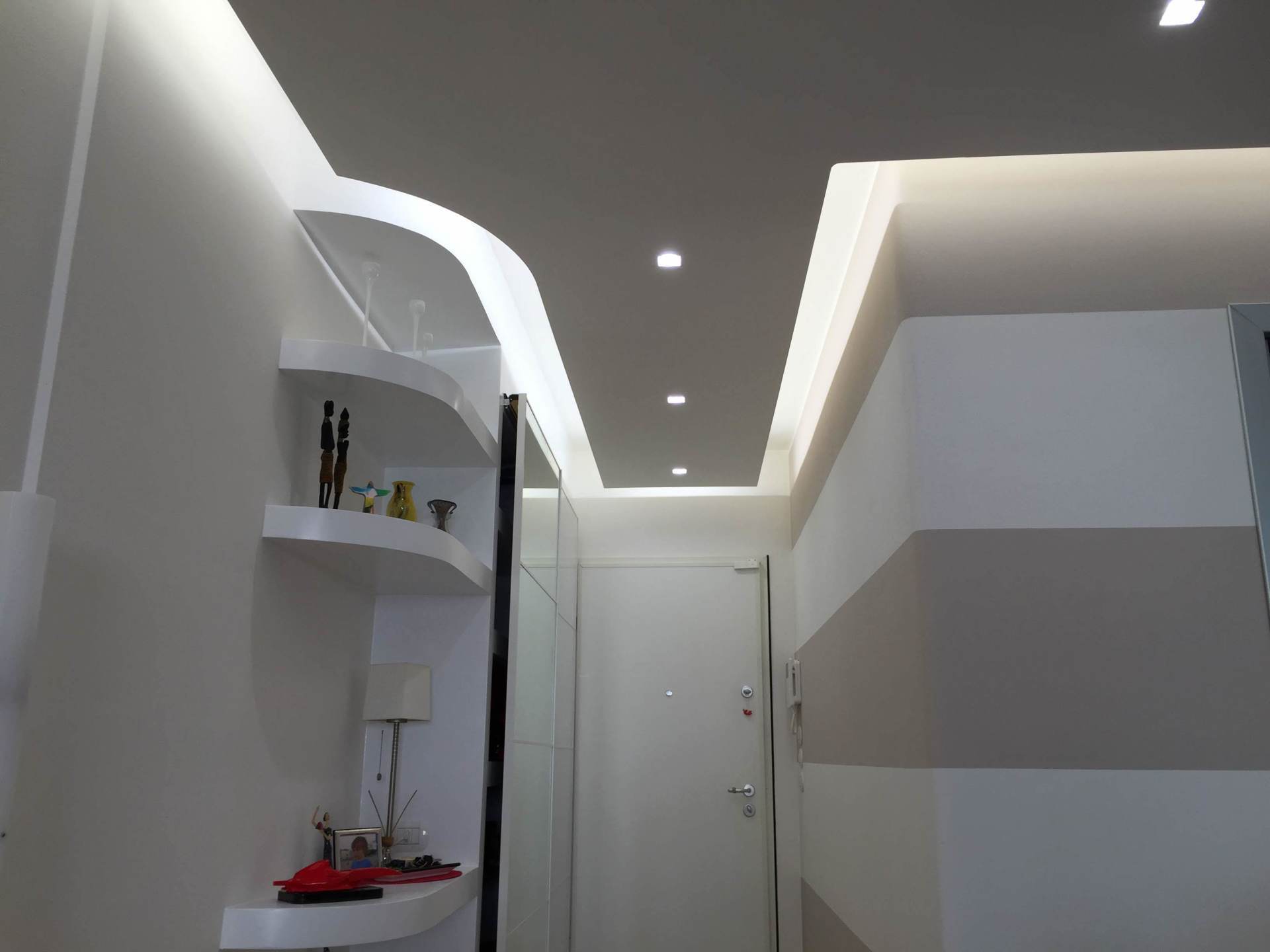 Corridoio bianco con illuminazione a incasso nel soffitto.