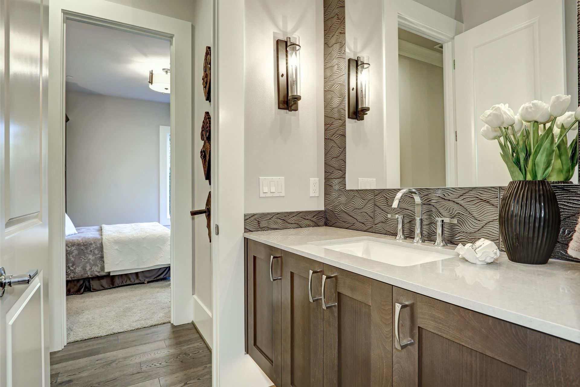 A bathroom with two sinks , a mirror and a vase of flowers.