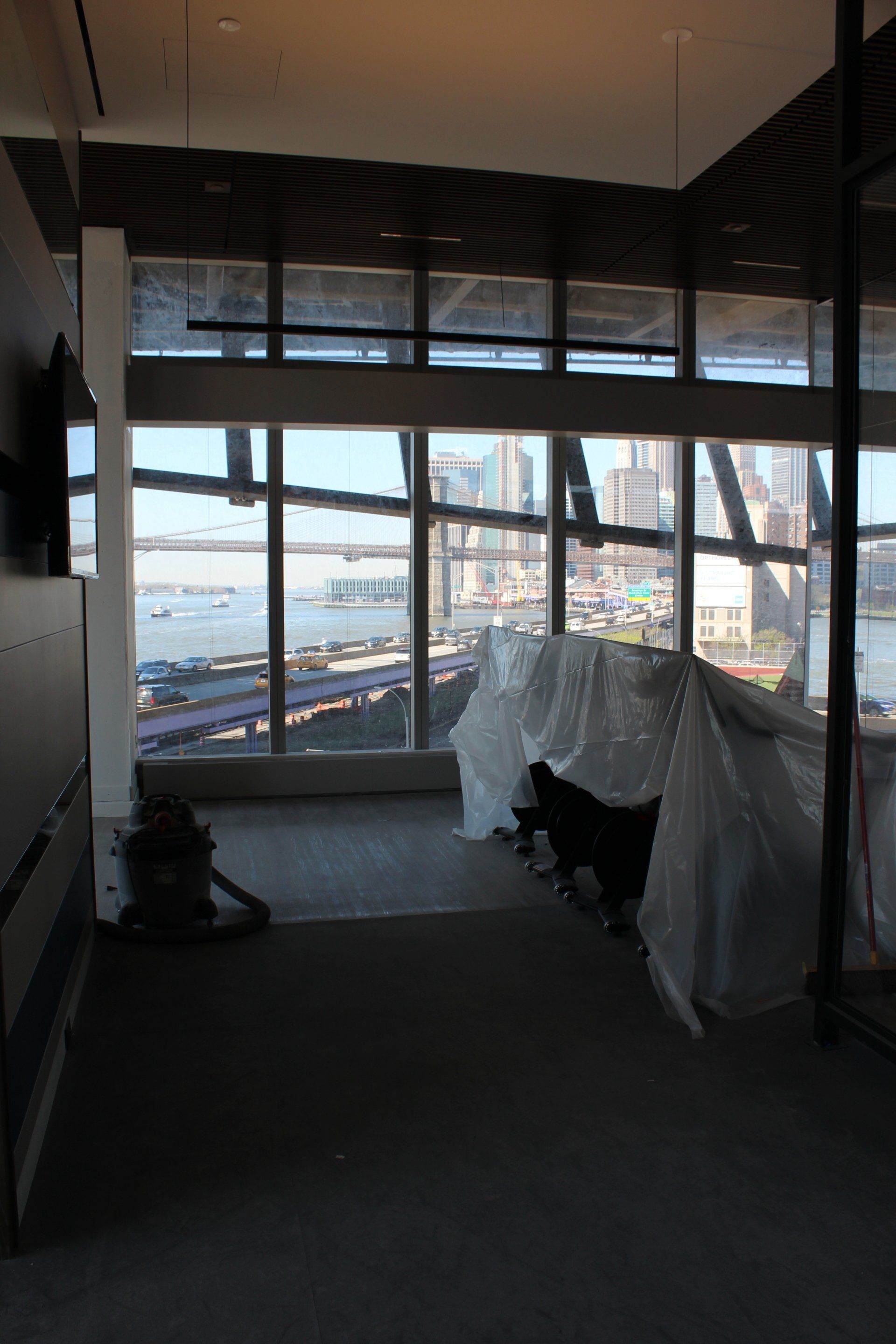 Treadmills covered for setup with large windows overlooking NYC skyline and waterfront.