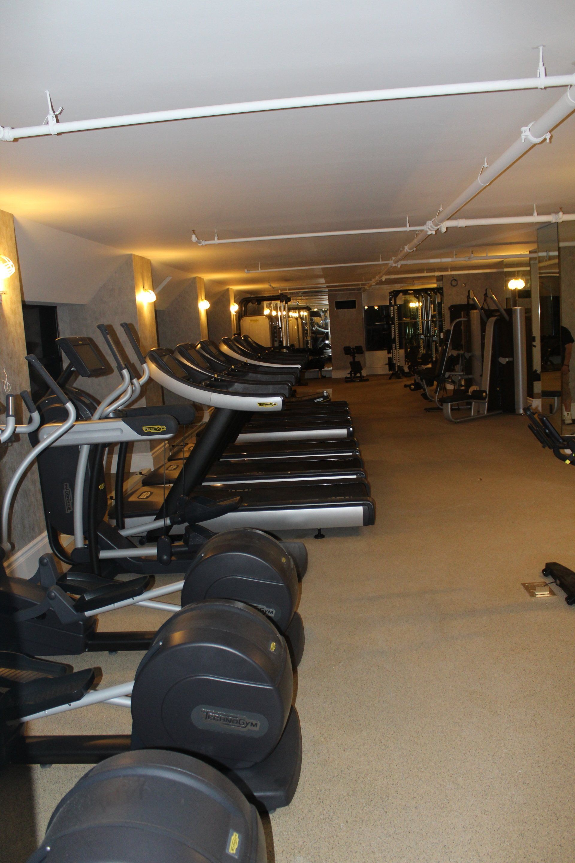 Row of treadmills in modern hotel fitness center with large mirrors.