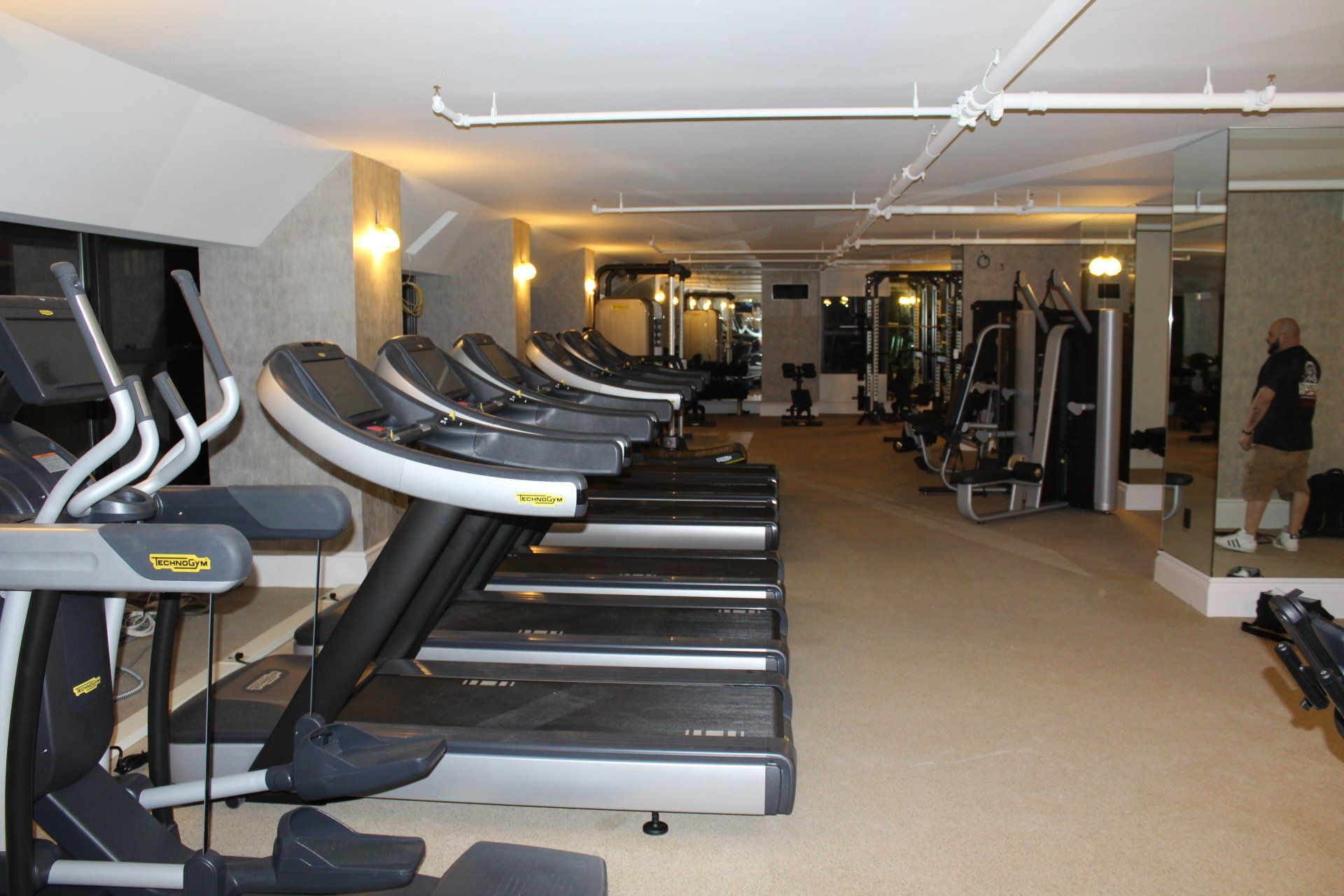 Bright fitness studio featuring multiple treadmills and modern strength training machines
