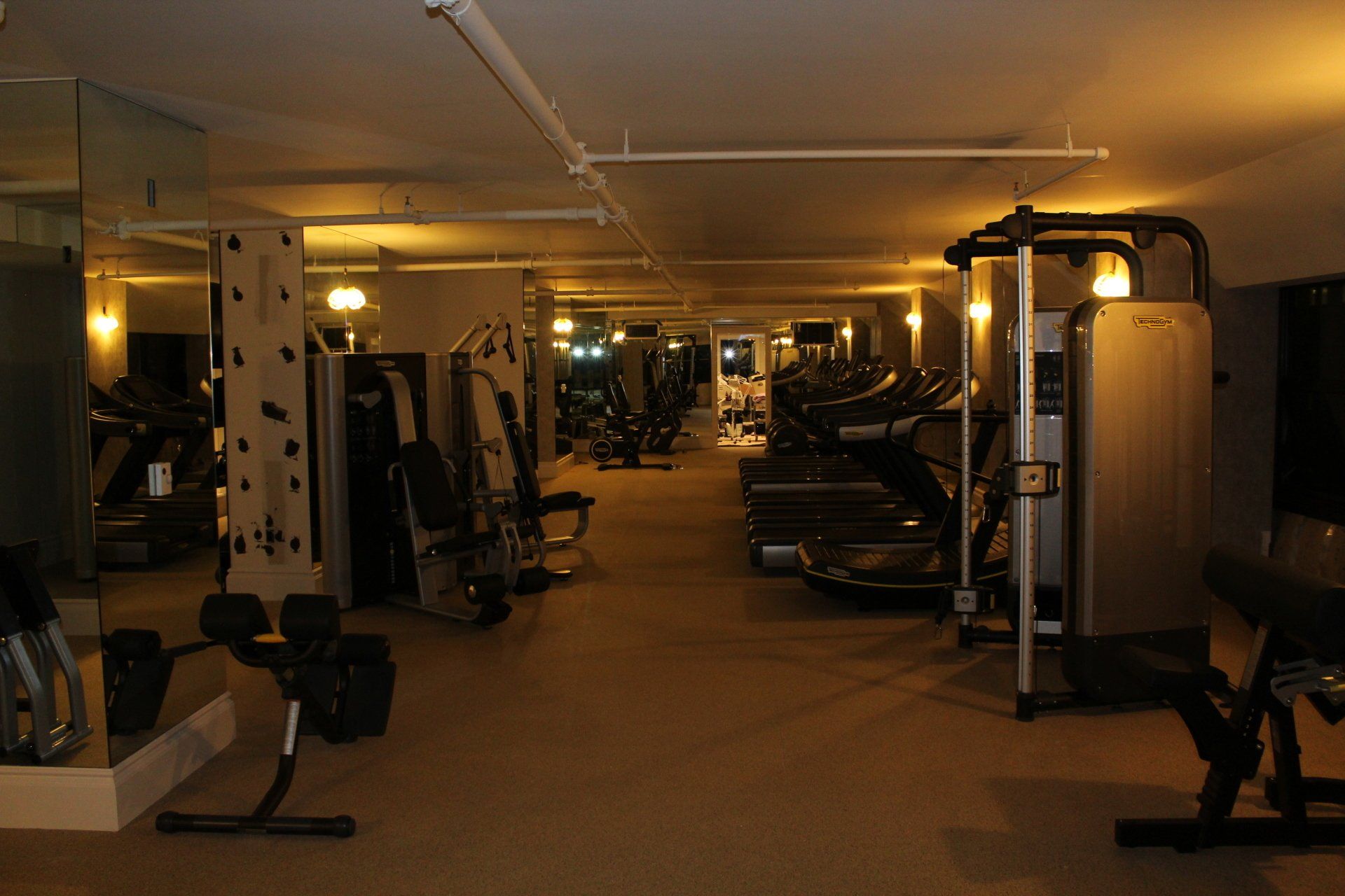 Hotel fitness center with cardio and strength equipment in warm lighting.