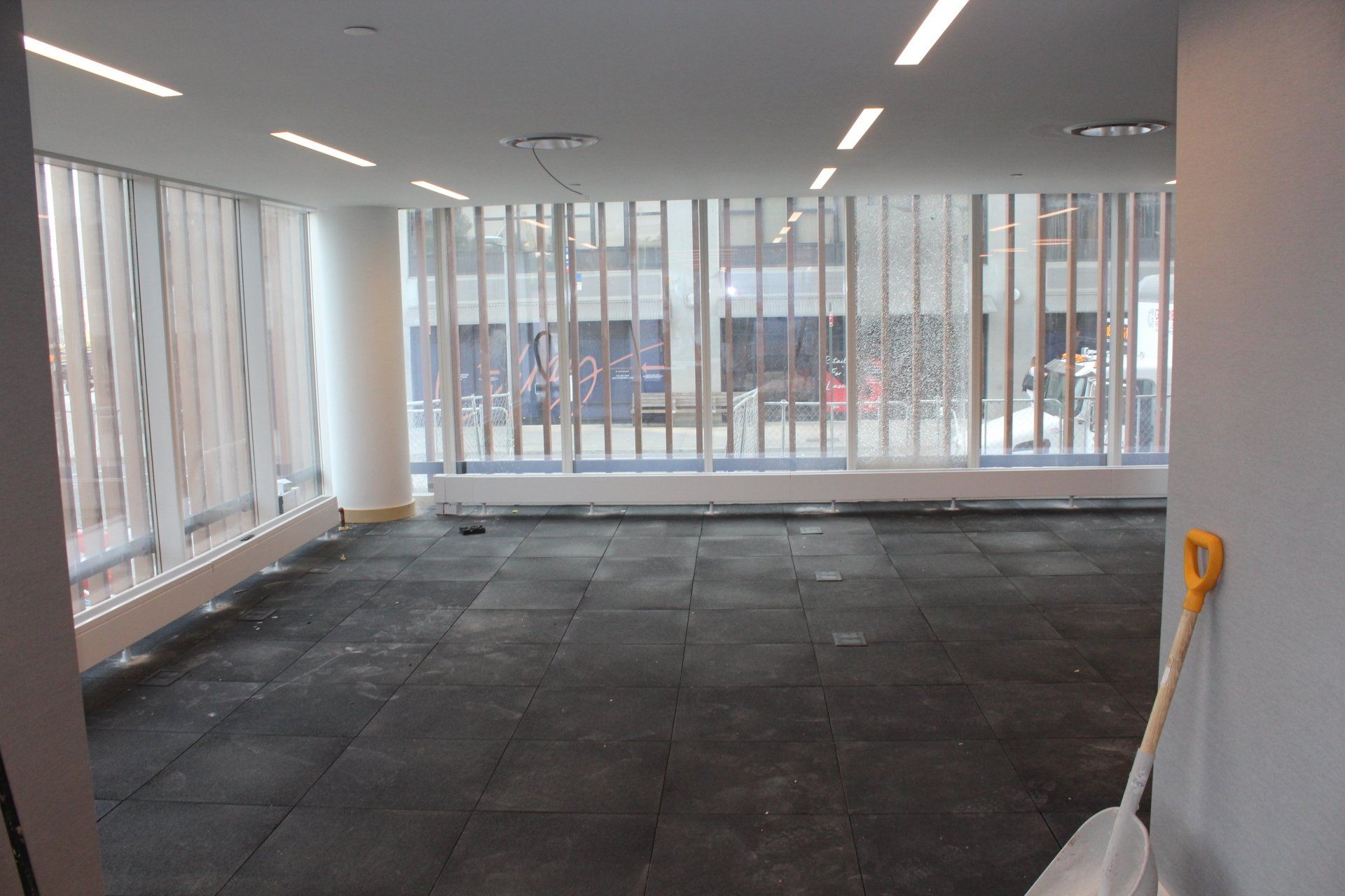 Large room at Quay Tower with new dark flooring and floor-to-ceiling windows during renovation.