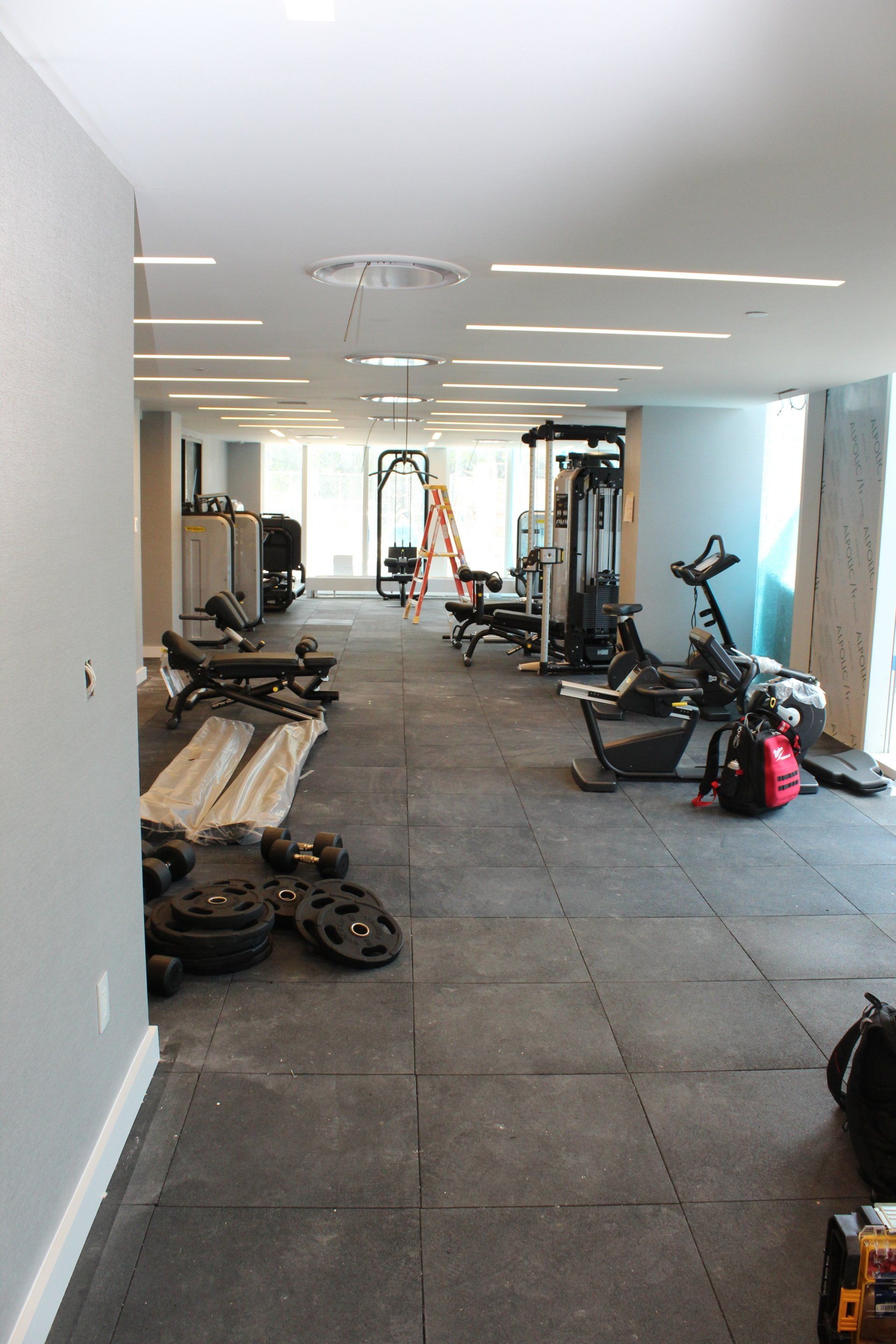 Quay Tower fitness center under construction with gym equipment and weights on the floor.