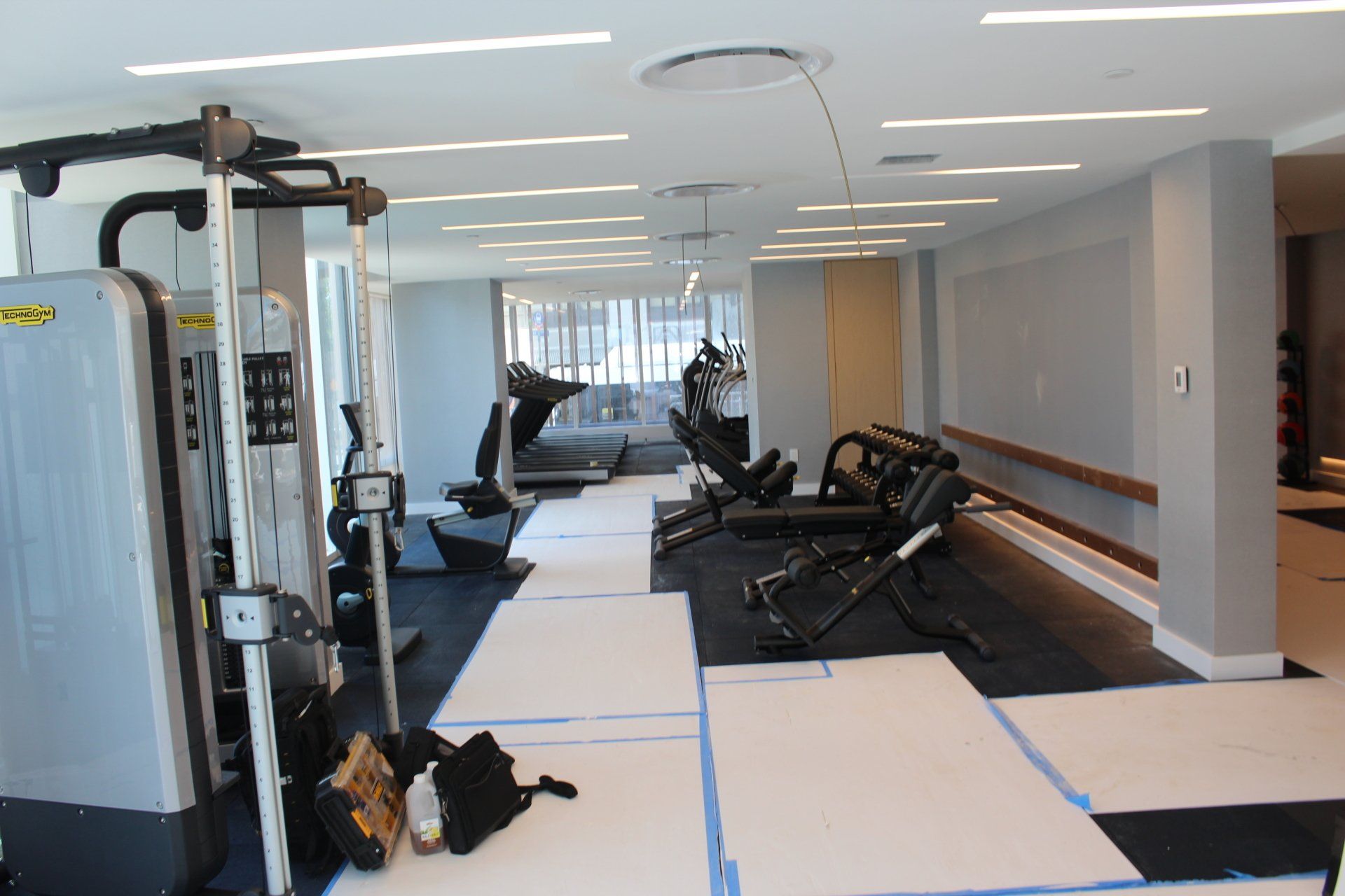 Quay Tower gym in progress with weight machines, benches, and covered flooring.