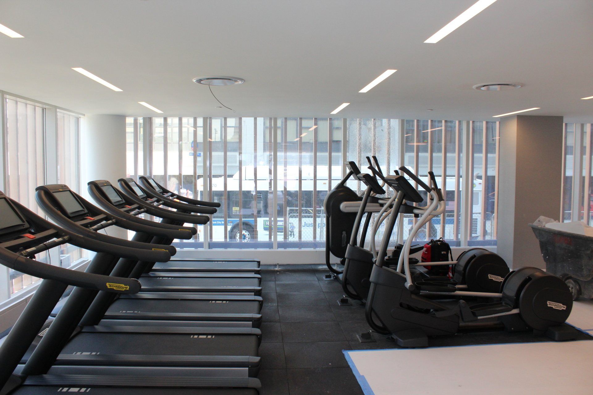 Treadmills and gym equipment in a bright fitness facility with large windows