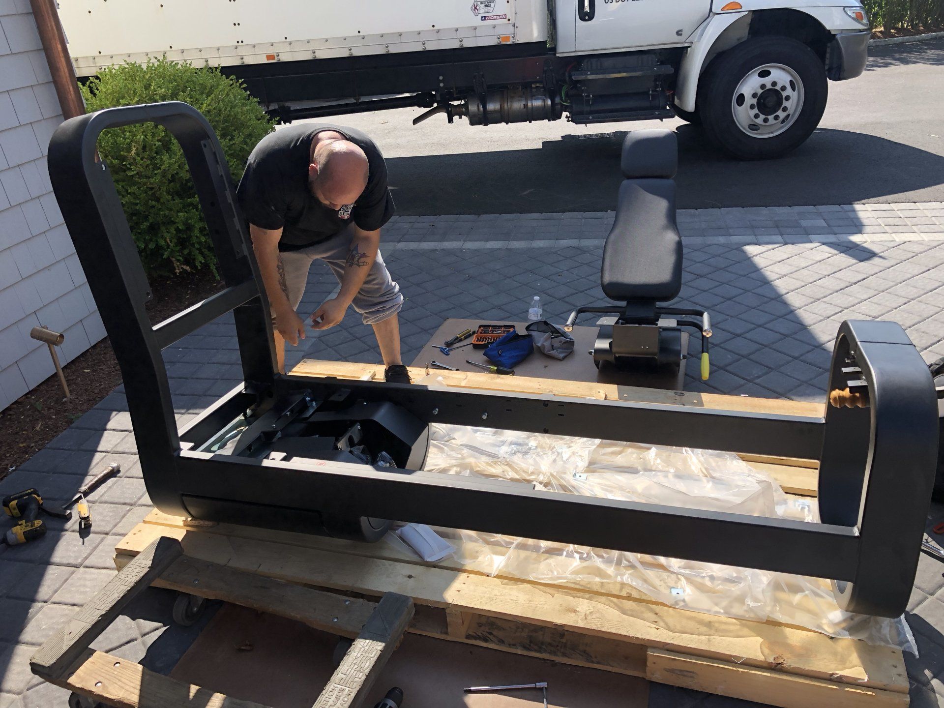 Worker assembling gym equipment frame outdoors during residential build in Bridgehampton.