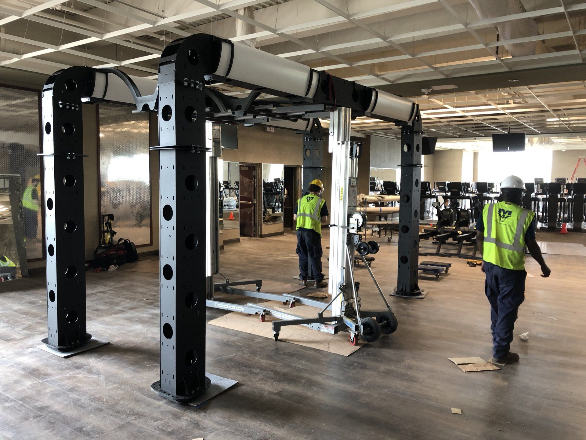 Technicians installing weightlifting machines on Lifetime Athletics gym floor.