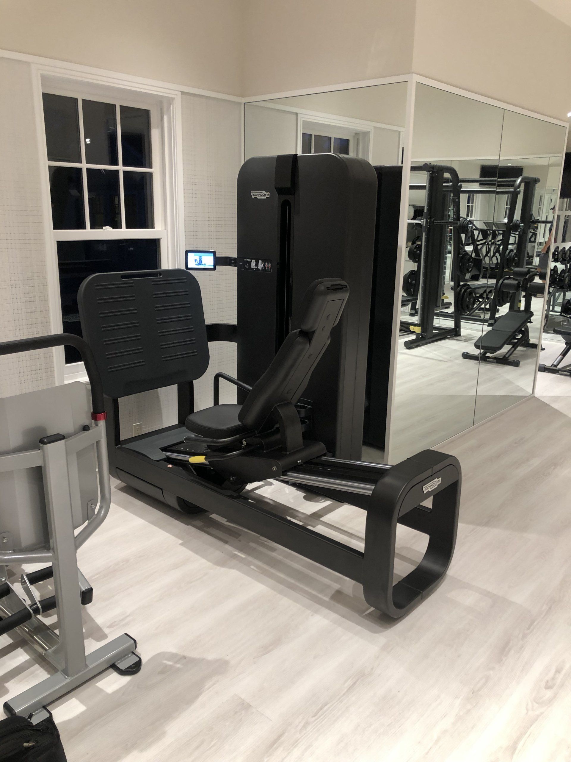 Leg press strength machine in a gym with mirrors and resistance equipment