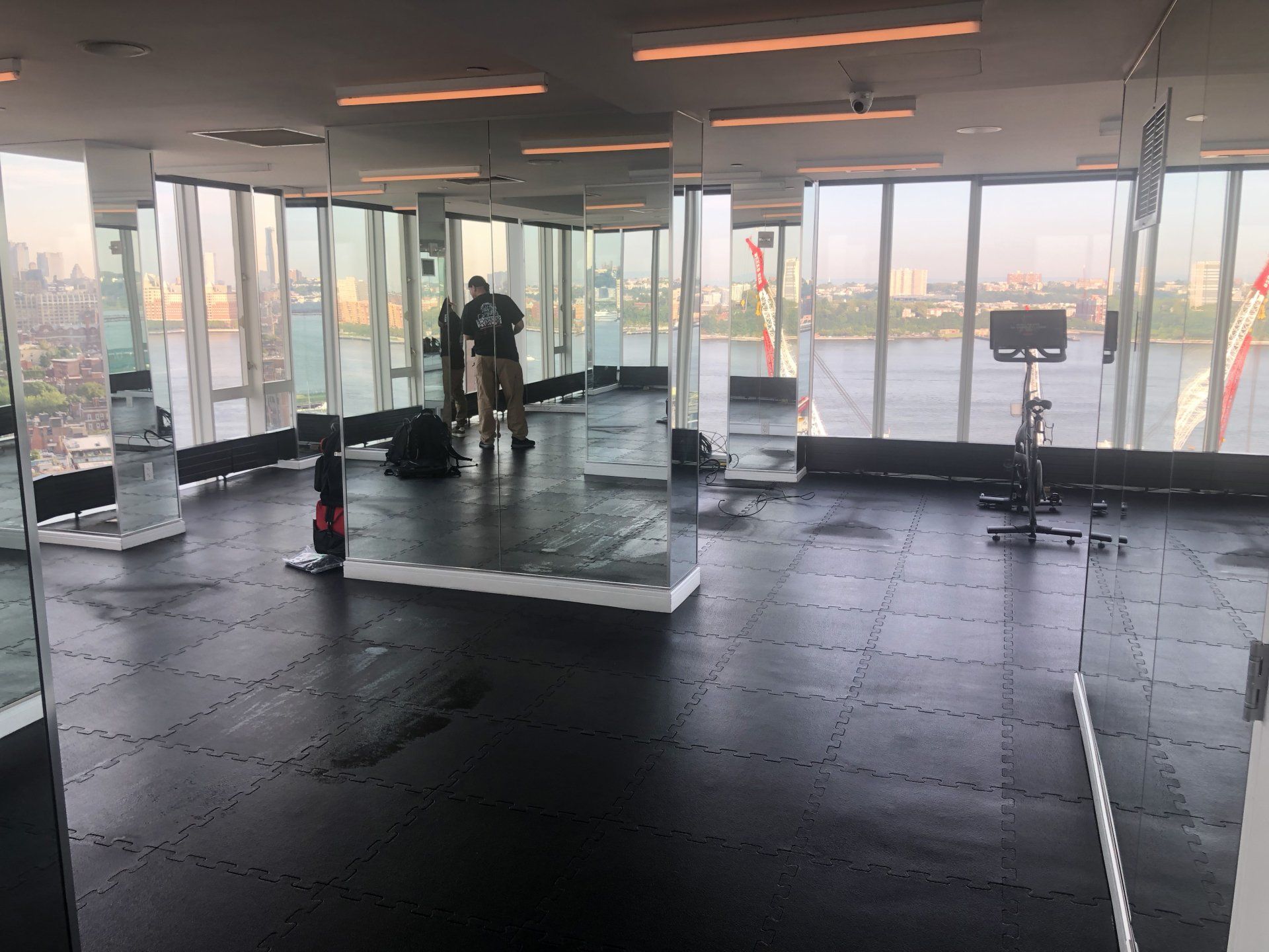 Gym mirror wall with exercise equipment and city skyline views at The Standard fitness facility.