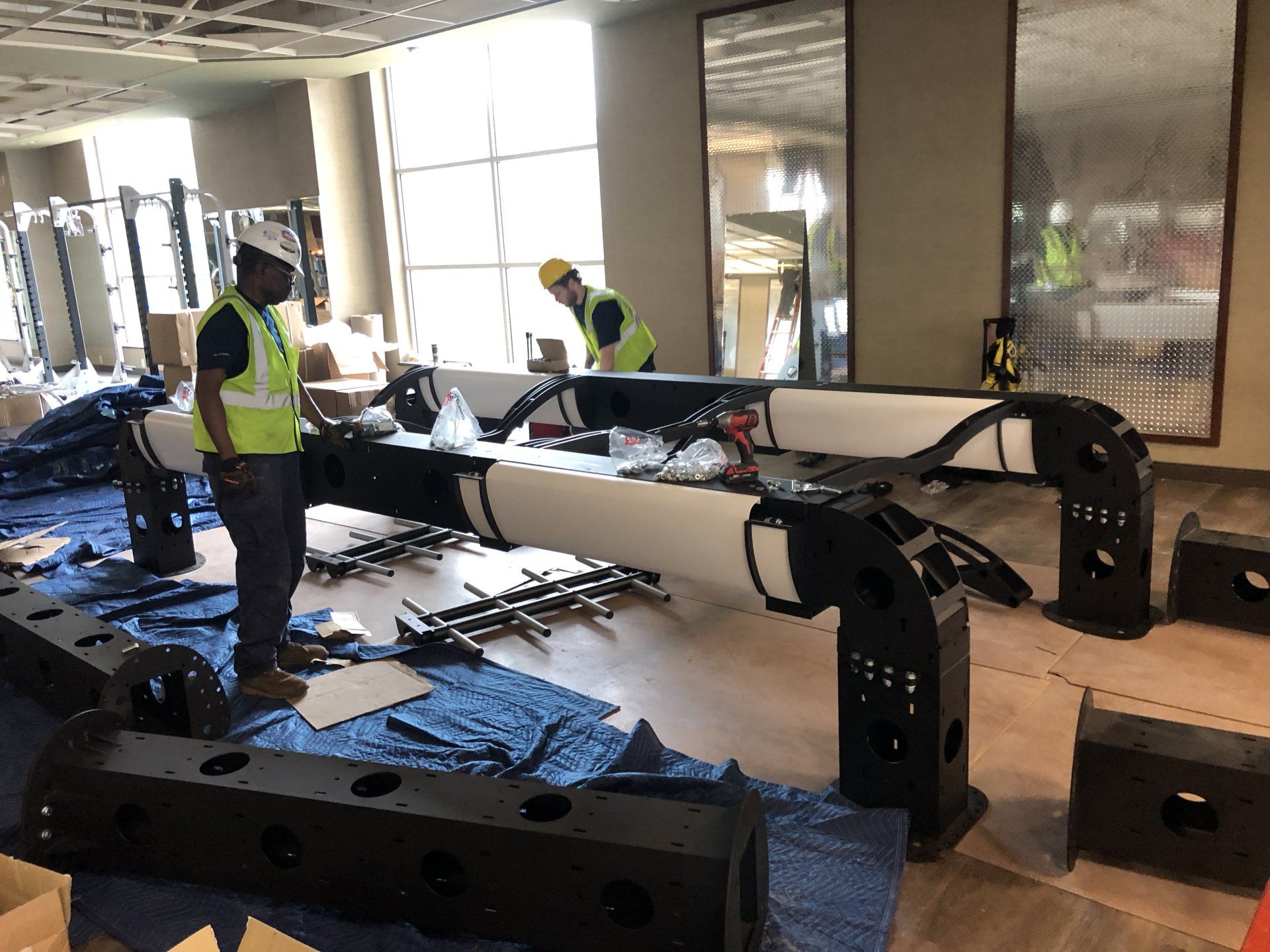 Construction workers assembling gym equipment at Lifetime Athletics fitness center.