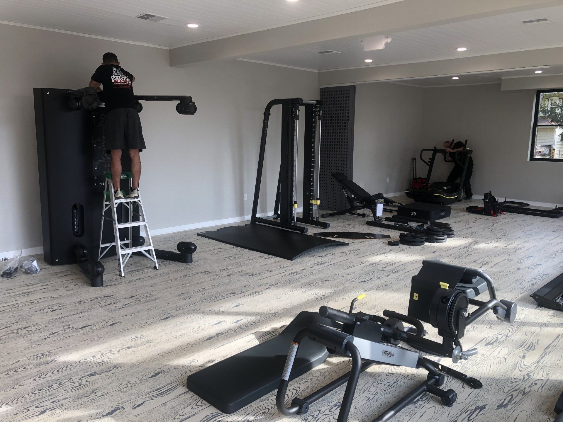 Technician setting up fitness machine in a bright Daily Fitness studio.