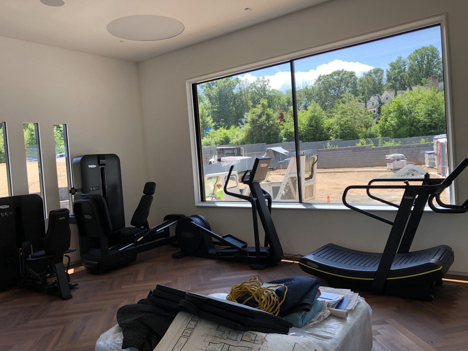 Modern home gym with weight machines and large windows at Bernardsville residential build