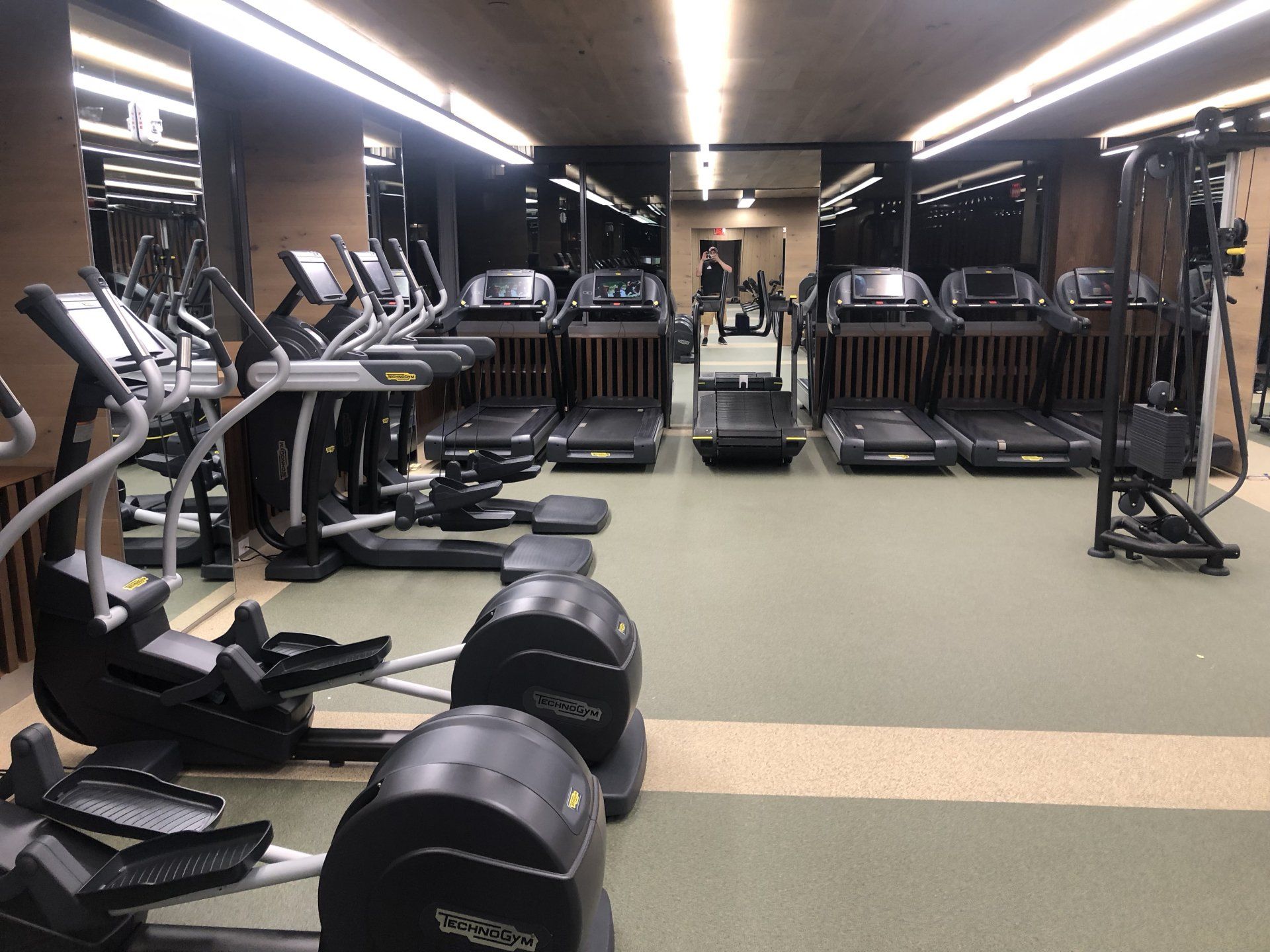 Wide gym view with multiple treadmills and ellipticals.