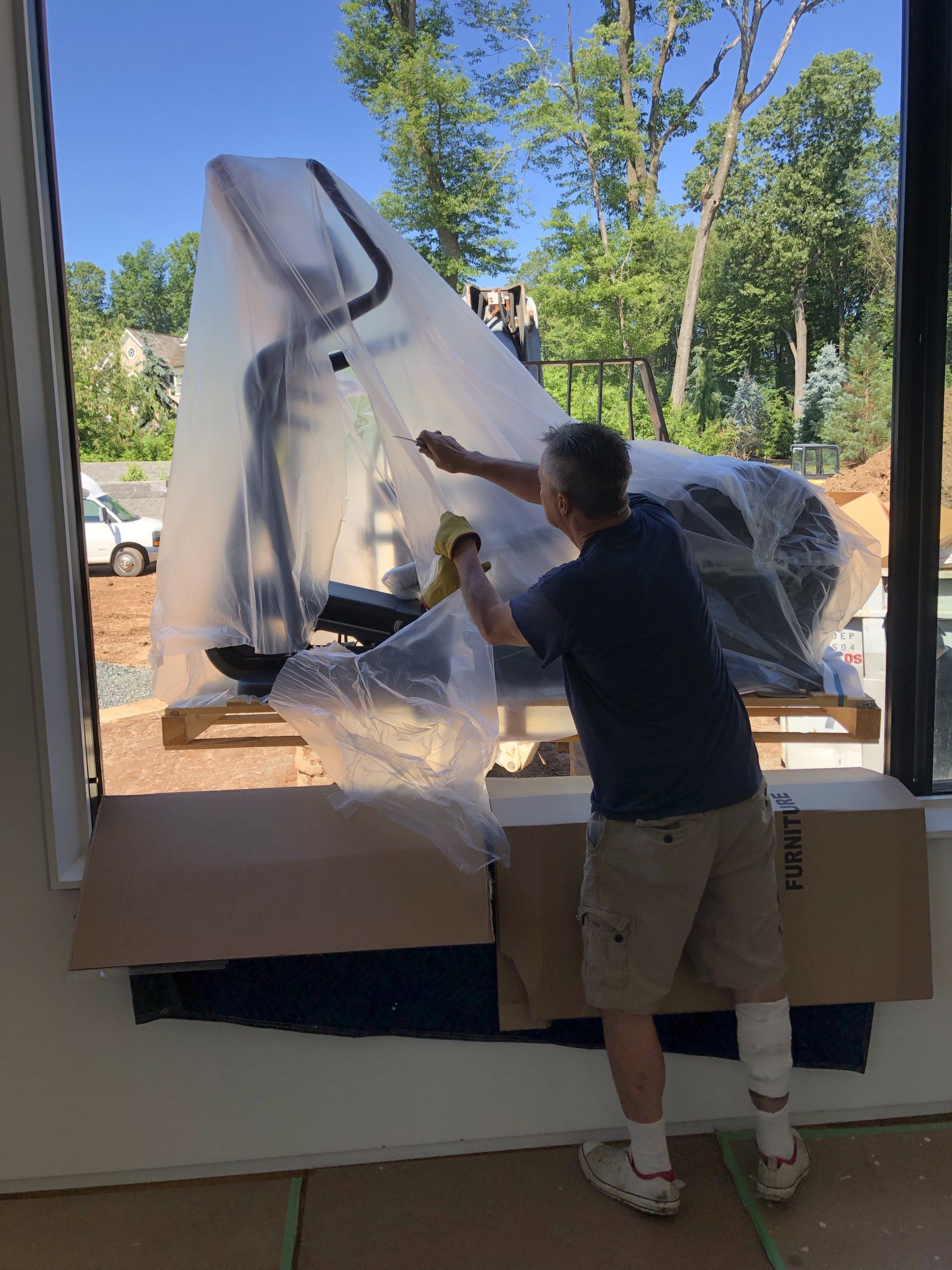 Crew member unwrapping fitness equipment for installation inside Bernardsville residential home gym.