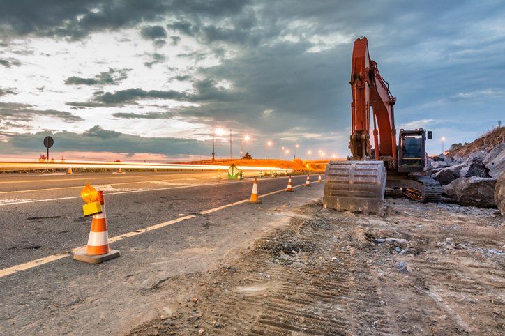 Works of extension of a road with excavator and delimited by safety cones