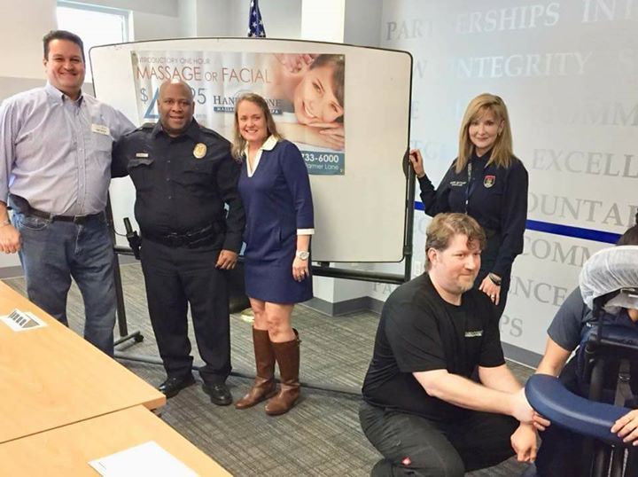 A group of people standing in front of a white board that says massage facial