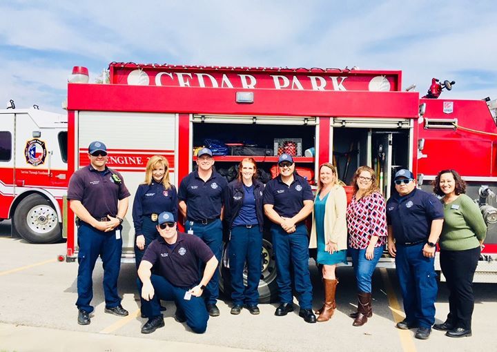 A group of firefighters are posing for a picture in front of a red fire truck.