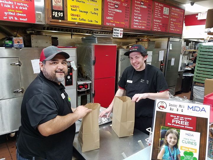 Two men are standing at a counter in a restaurant.