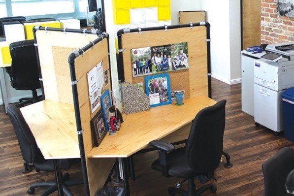 A cubicle with a wooden desk and chairs in an office