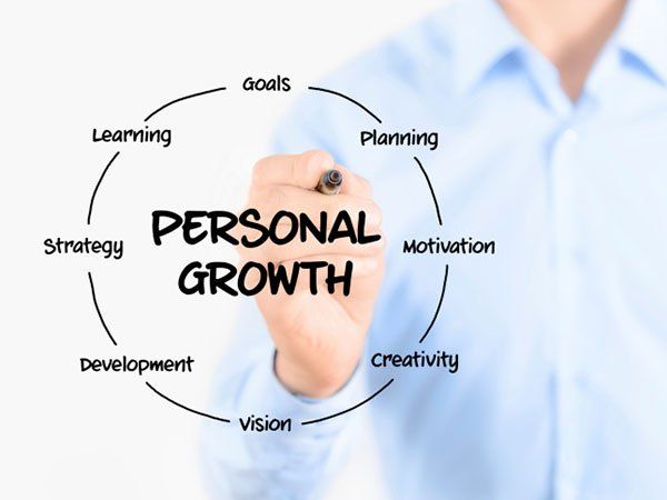 A man is writing the word personal growth with a marker
