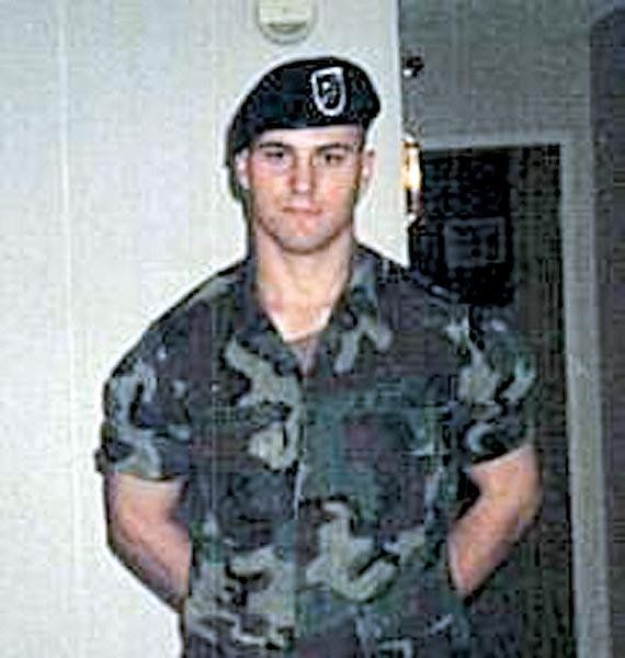 A man in a military uniform and beret is standing in front of a door.