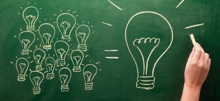 A person is drawing a light bulb on a blackboard