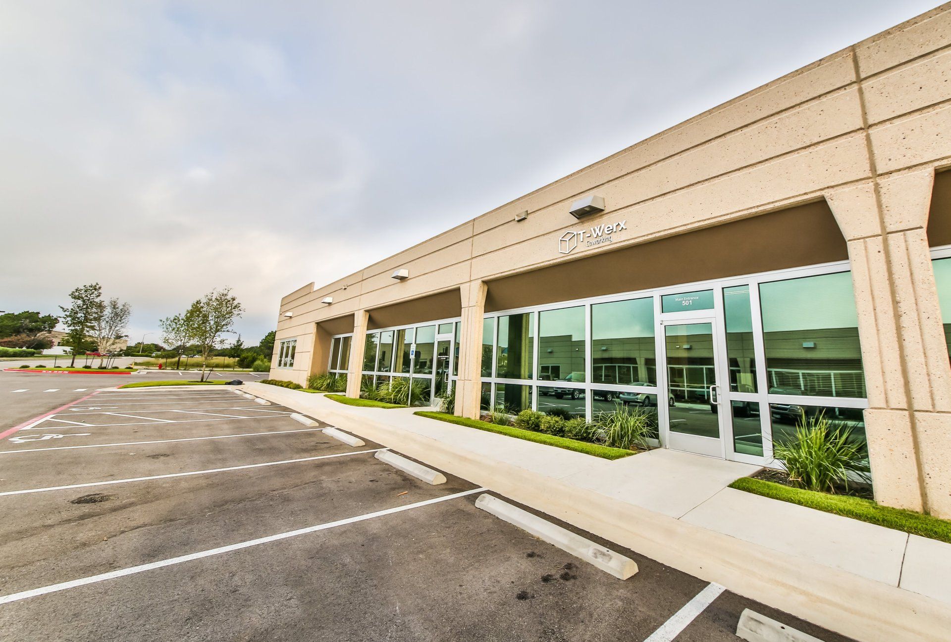 A large building with a lot of windows and a parking lot in front of it.
