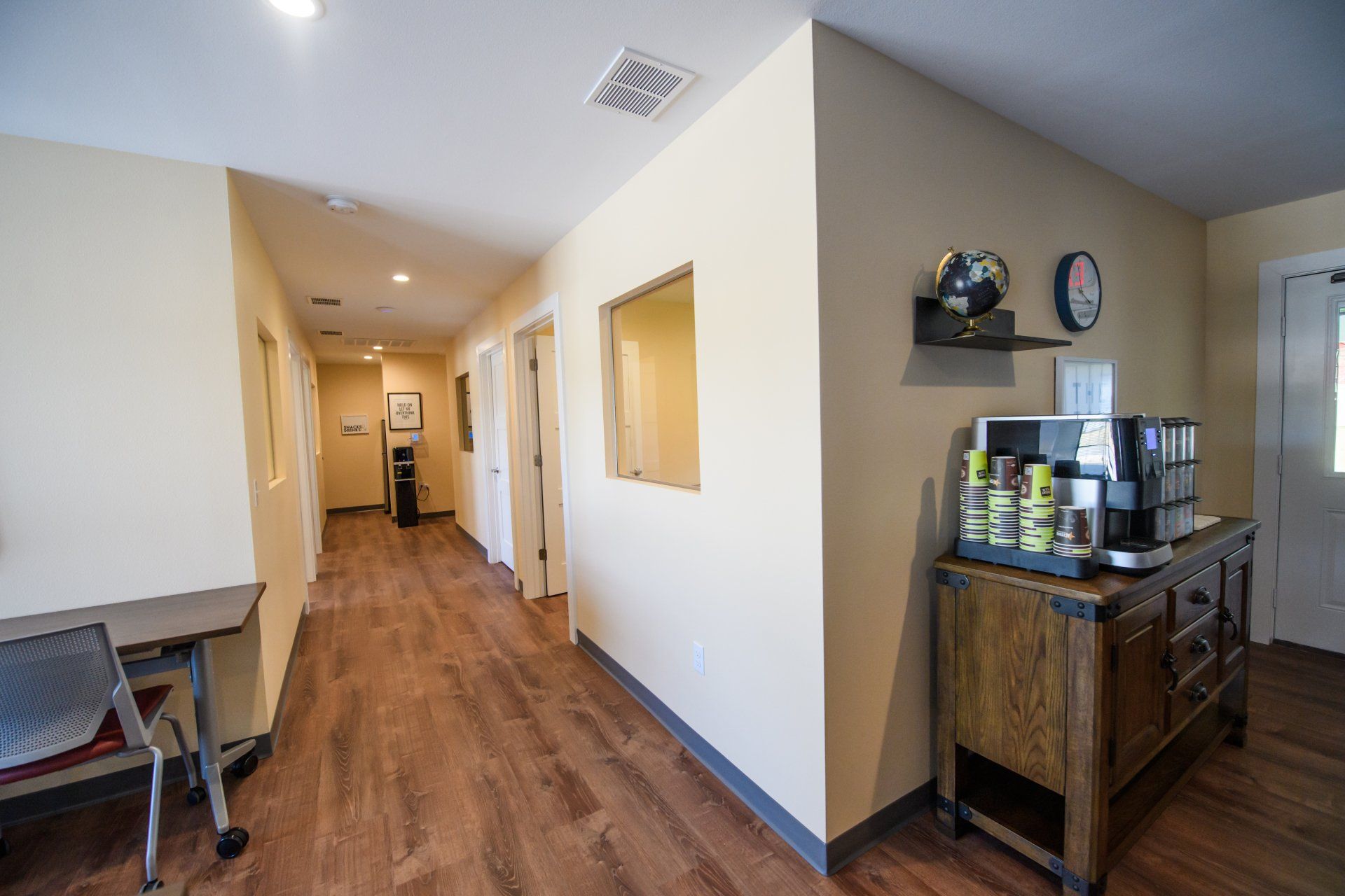 A long hallway with wooden floors and a clock on the wall.