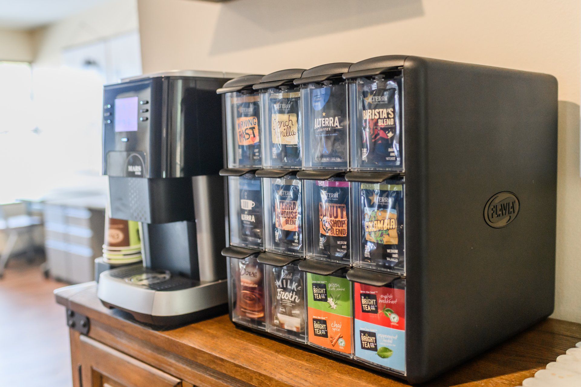 A coffee machine is sitting on a wooden table next to a coffee dispenser.