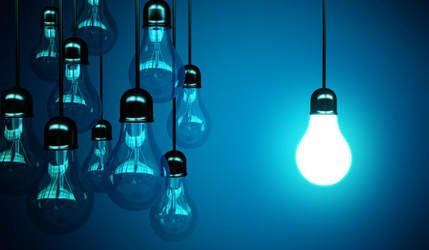 A group of light bulbs hanging from the ceiling with one glowing brightly.