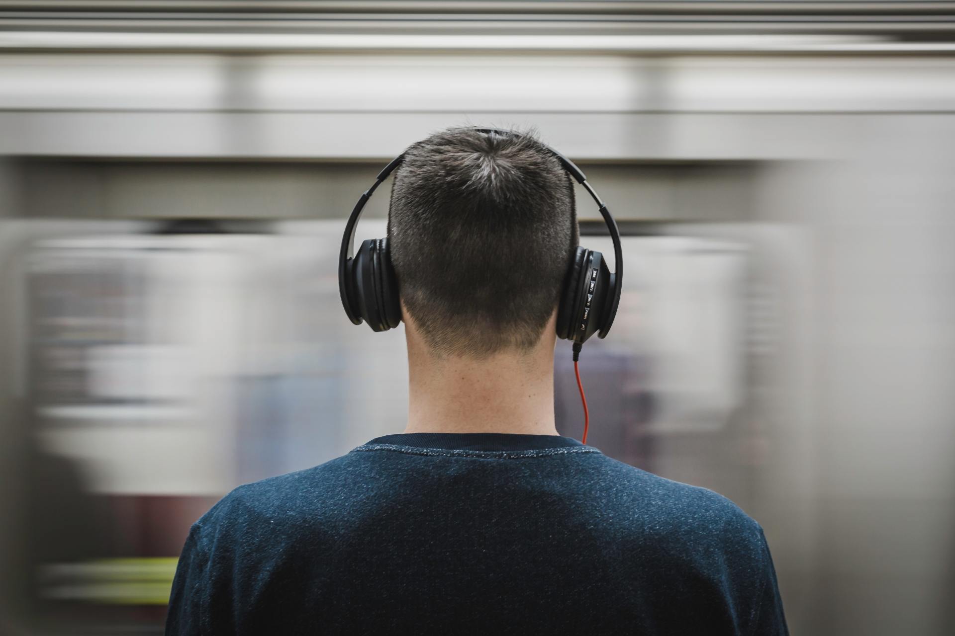 A man wearing headphones is sitting on a train.