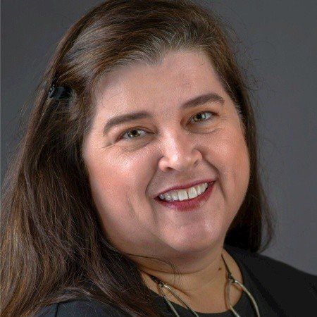 A woman with long brown hair is smiling for the camera.