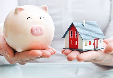 Person Holding Piggy Bank and Model House  — Olympia, WA — Bliss & Skeen, CPAs