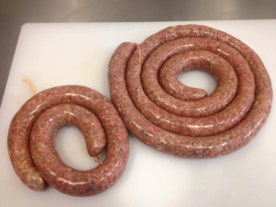 Two swirls of sausage are sitting on a white cutting board.