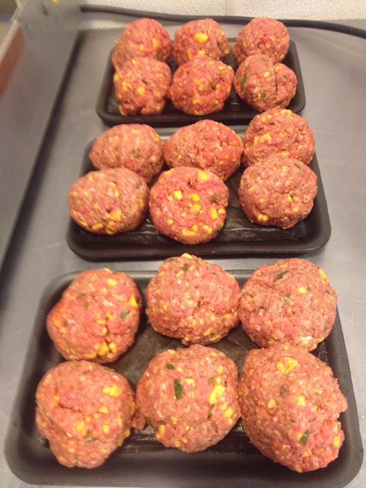 Three trays of meatballs are sitting on a counter.