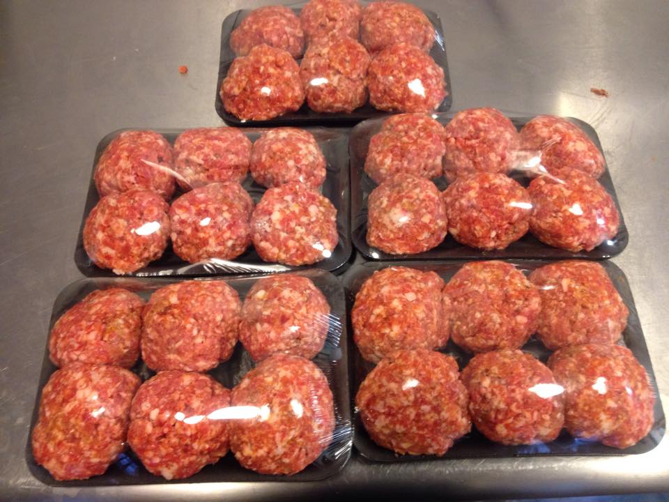 Three trays of meatballs are stacked on top of each other on a counter.