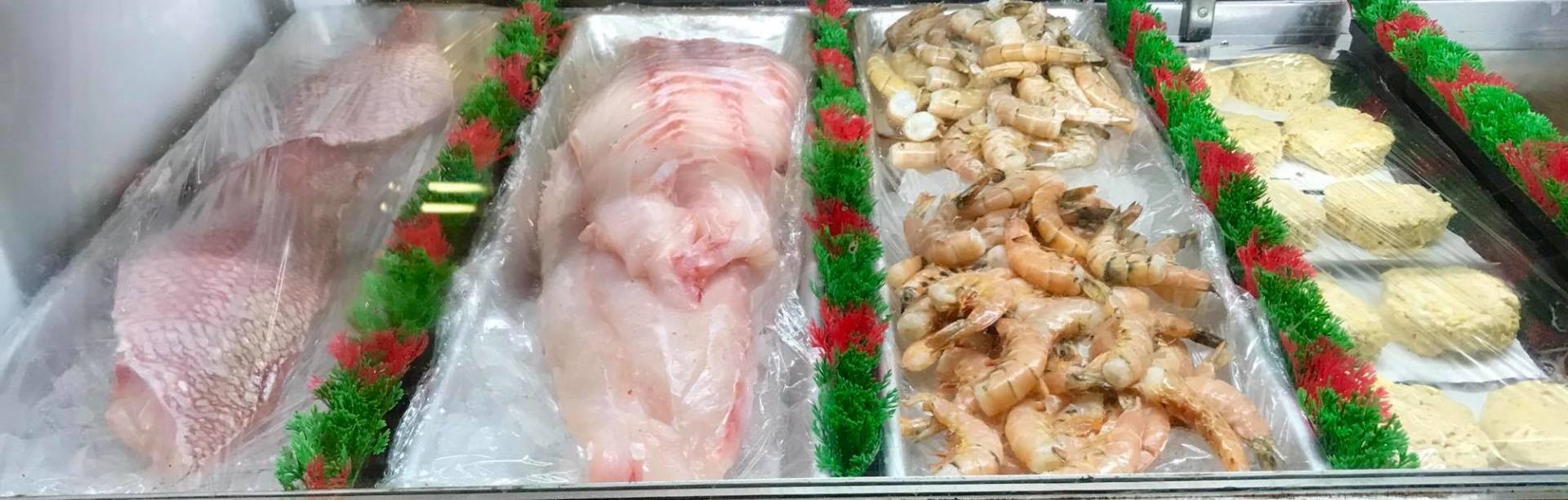 A display case filled with a variety of meats and shrimp.