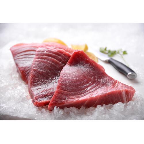 Three pieces of raw tuna are sitting on top of ice.