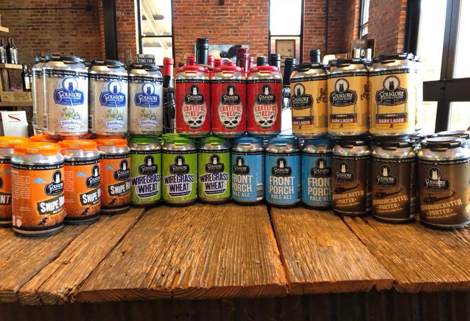 A row of cans of beer are lined up on a wooden table.