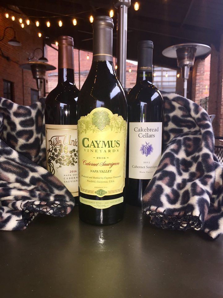 Three bottles of wine are sitting on a table next to a leopard print blanket.