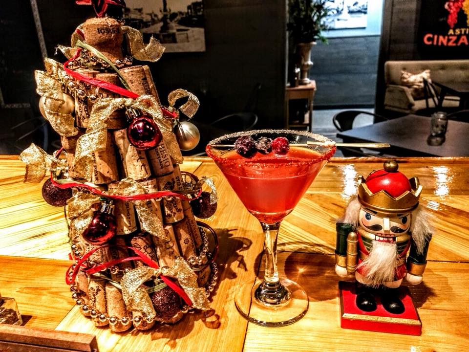 A nutcracker is standing next to a martini glass on a wooden table.